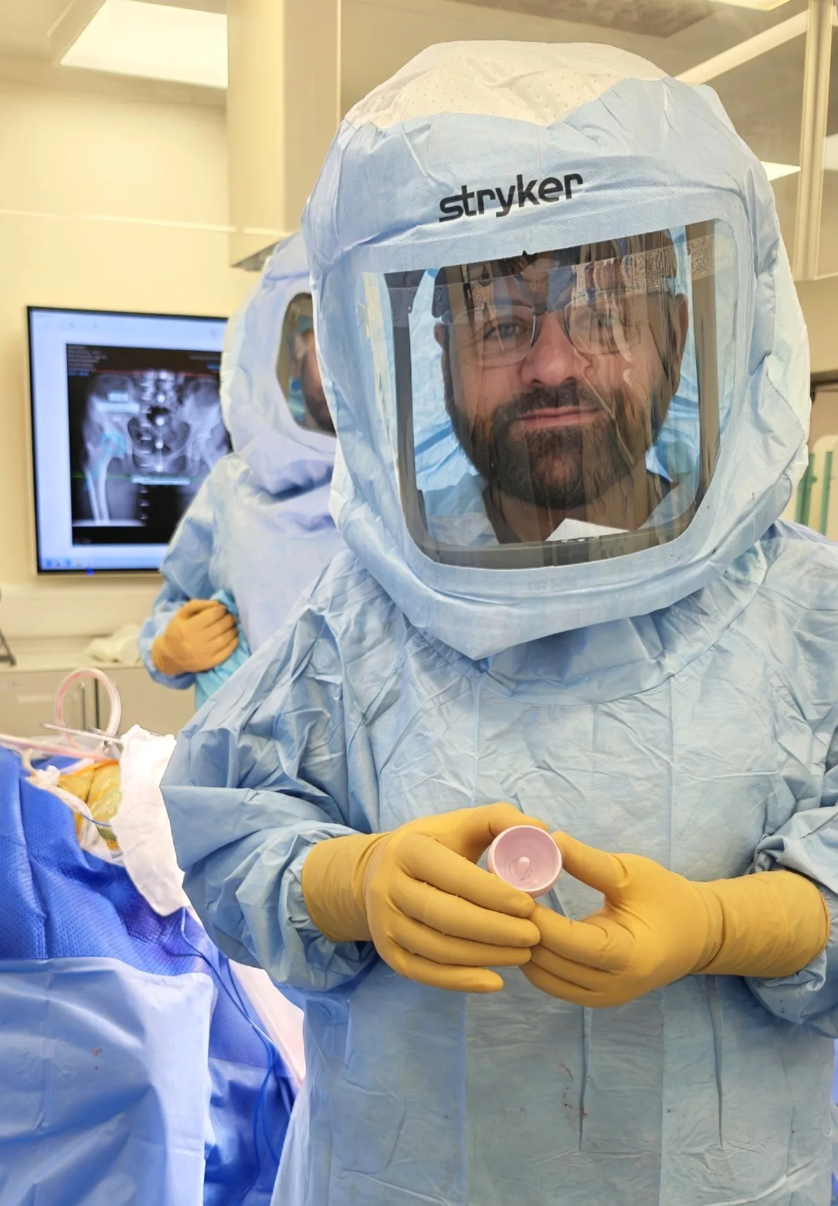 Mr Shakir Hussain holding a ReCerf ceramic-on-ceramic femoral cap in theatre before hip resurfacing surgery in Birmingham
